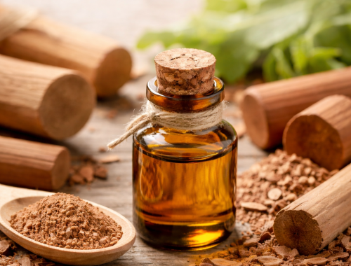 Sandalwood essential oil bottle with sandalwood powder and wood pieces on a rustic table