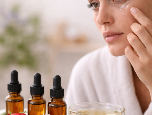 Woman applying essential oil for eye bags under her eyes with natural oils and flowers in a calm skincare setting.