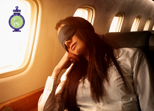 Traveler resting on an airplane seat wearing a sleep mask, illustrating the use of essential oils for jet lag relief during long-haul flights.