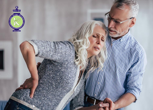 Older woman experiencing joint and lower back pain while being supported by her partner, illustrating natural wellness approaches including eucalyptus essential oil for joint discomfort.